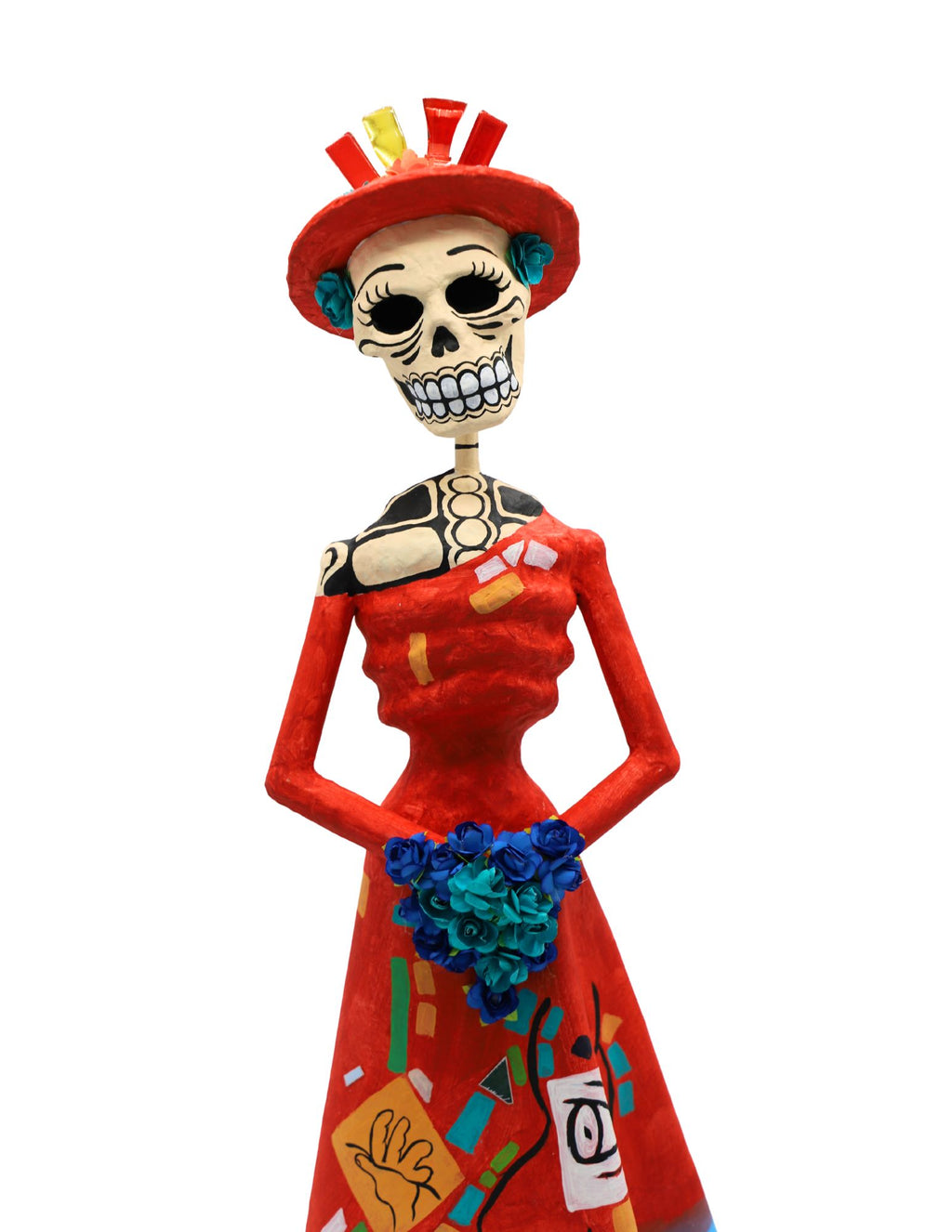 A papier-mâché skull figurine wearing a red dress and hat, holding a bouquet of blue flowers.