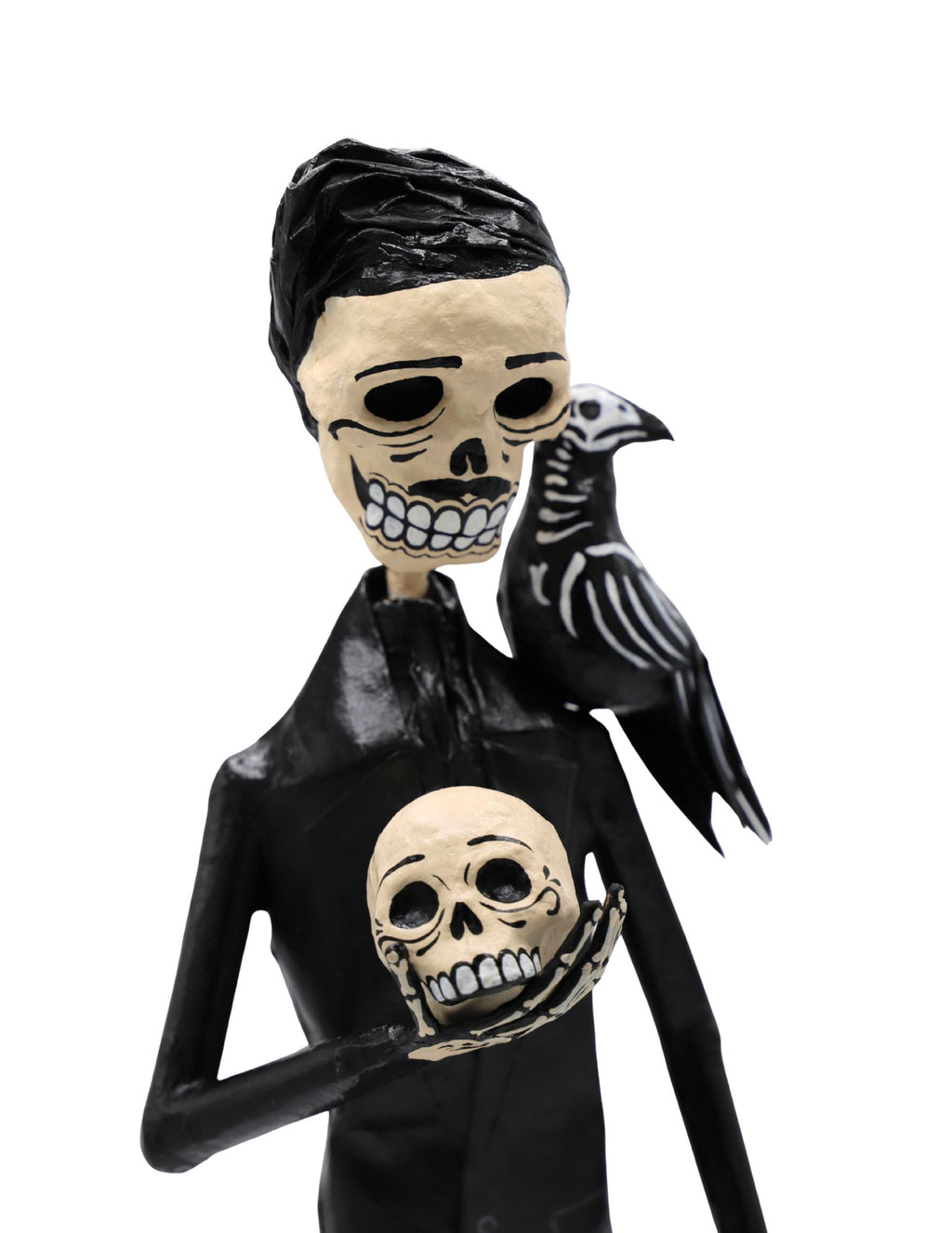 A papier-mâché skeleton figurine wearing a black suit and holding a skull with a black raven on its shoulder.