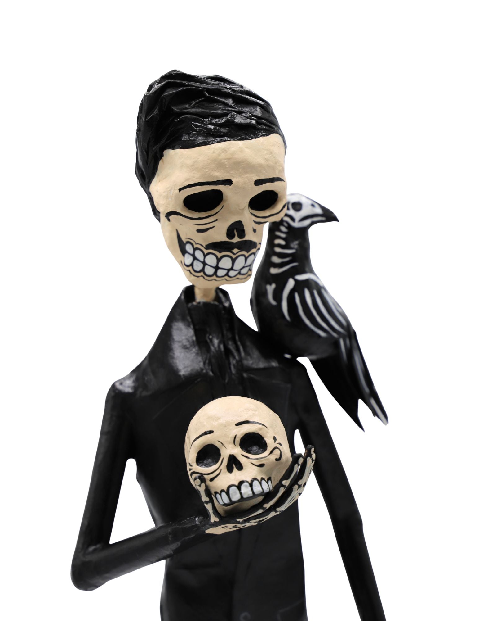 A papier-mâché skeleton figurine wearing a black suit and holding a skull with a black raven on its shoulder.
