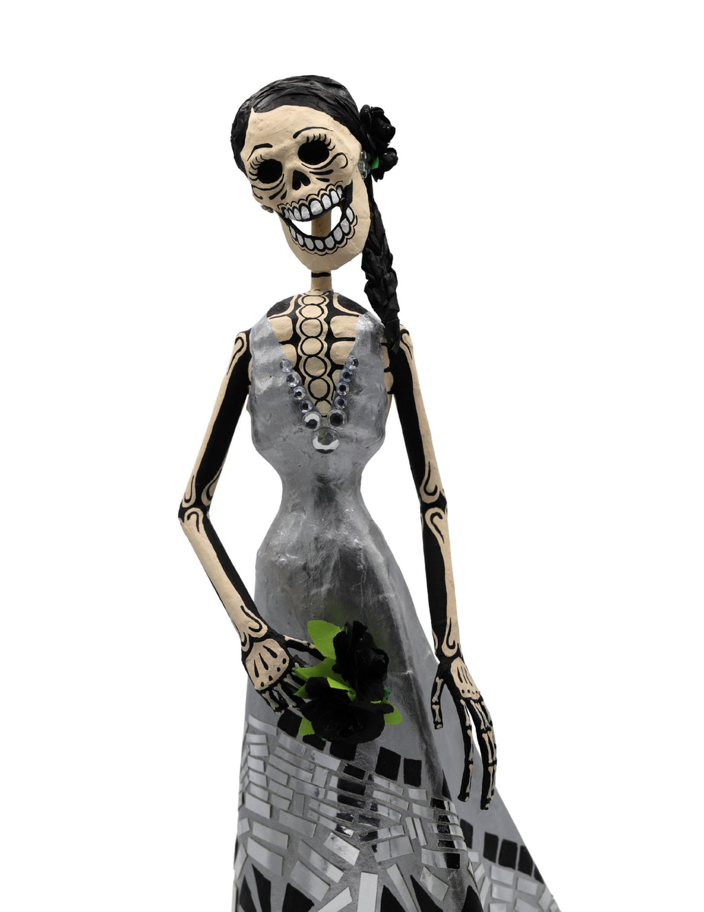 A papier-mâché skeleton with a black braided hair, wearing a gray dress with mosaicked patterns on it.