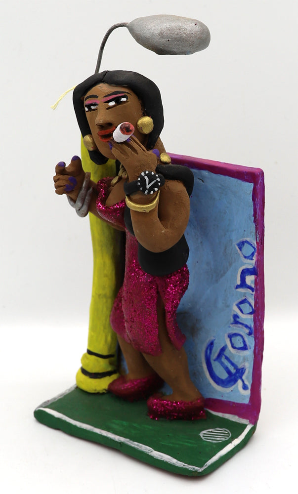 A ceramic figurine of a woman in a sparkly pink dress holding an oversized cigarette under a street light. 