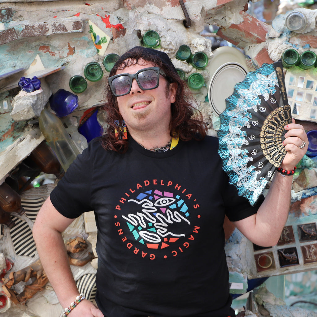 A woman holding a fan wears a black t-shirt with a colorful PMG logo on the front.