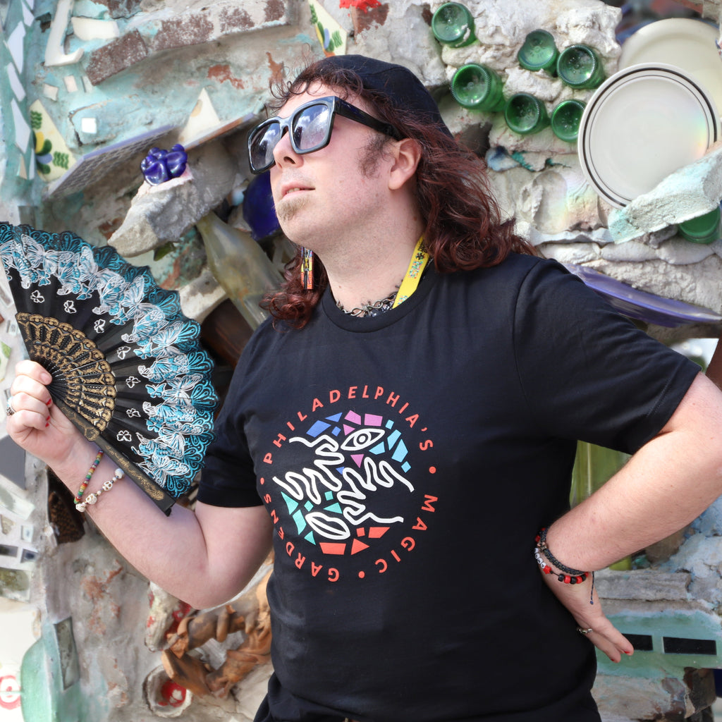 A woman holding a fan wears a black t-shirt with a colorful PMG logo on the front.