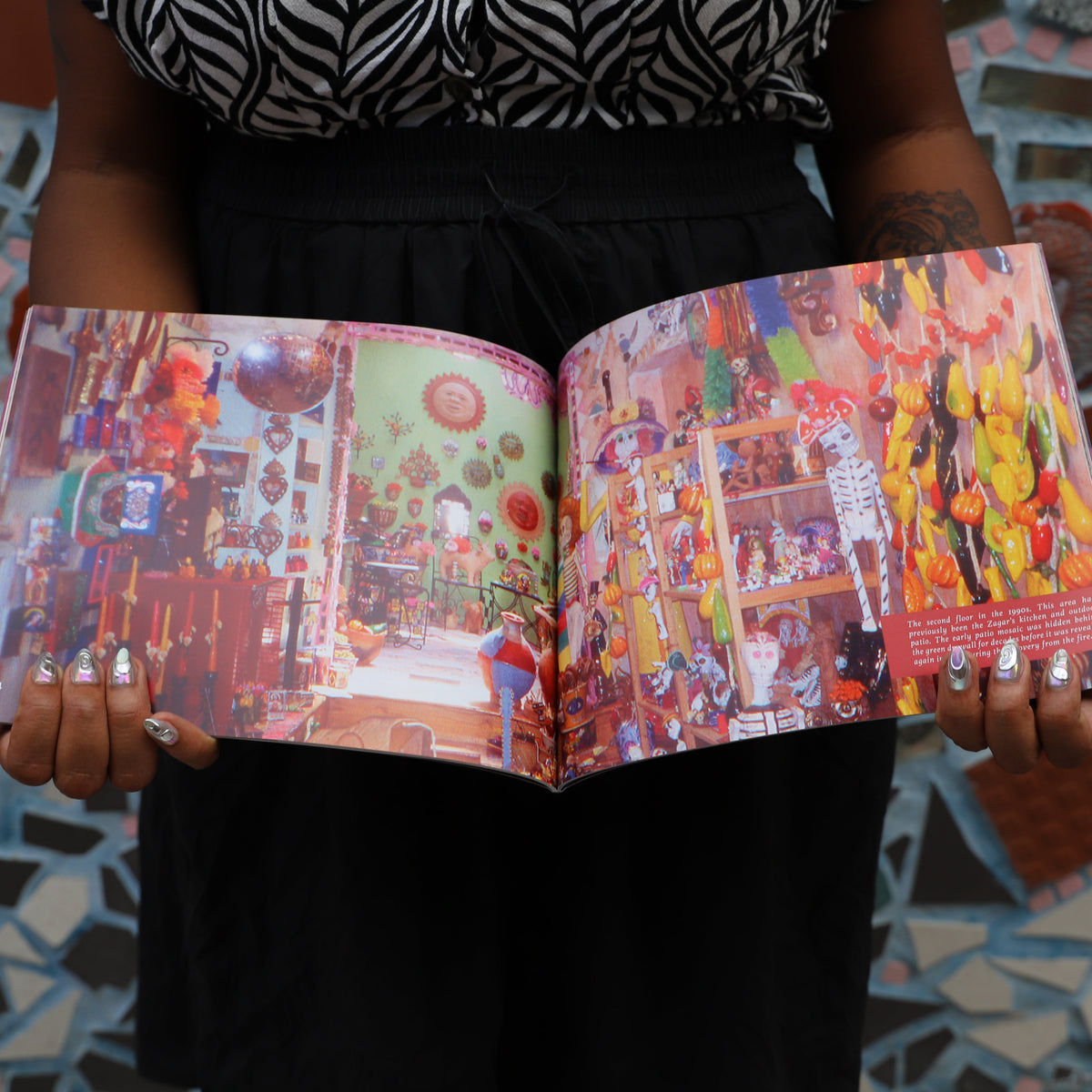 A woman holds open the Eye's Gallery book to a colorful full-page photograph