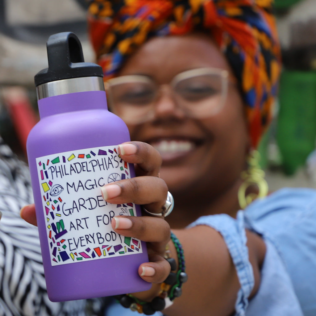 Three people hold water bottles with different PMG stickers on them.