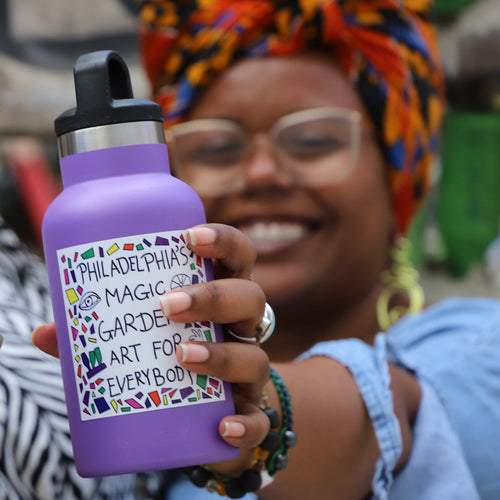 Three people hold water bottles with different PMG stickers on them.