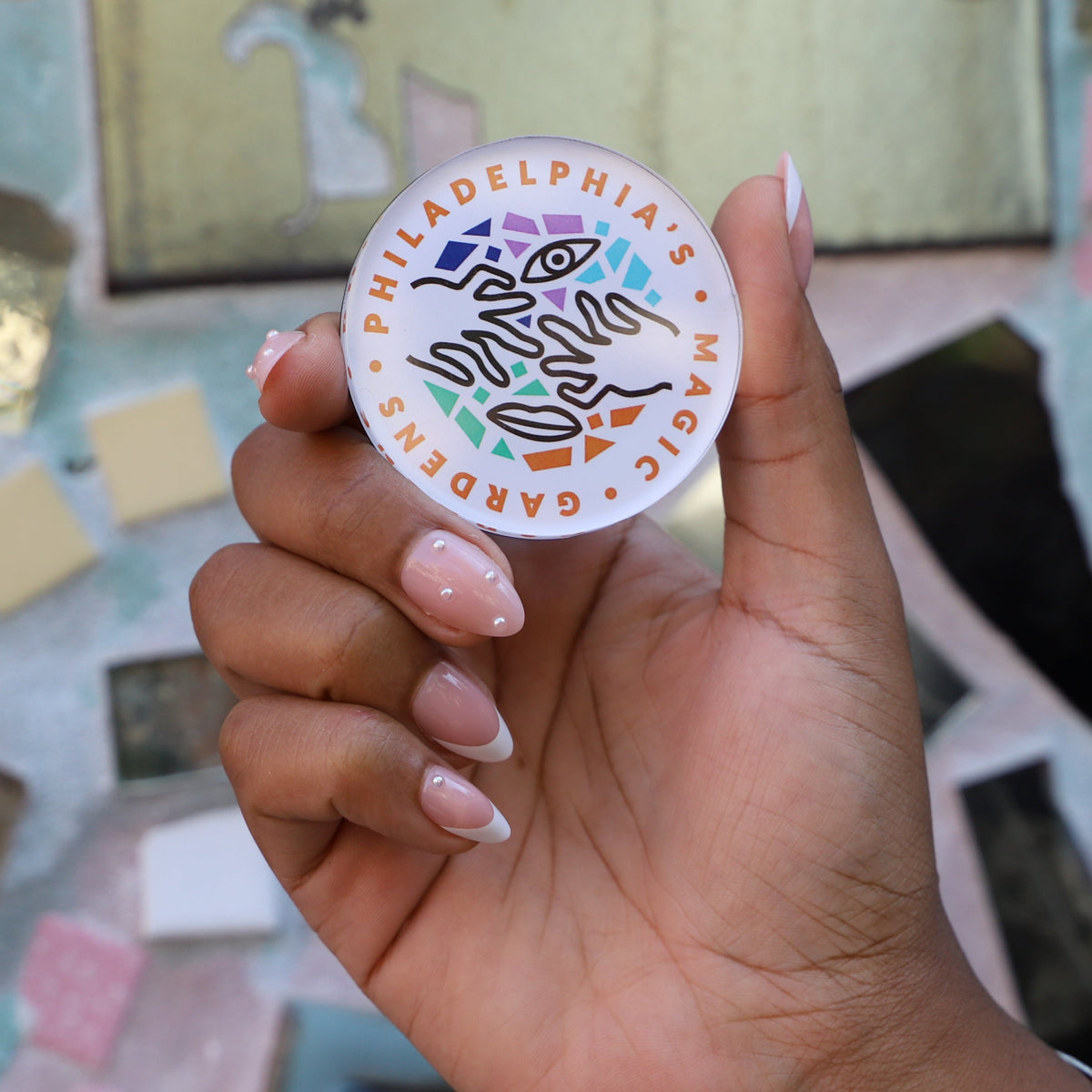 A round refrigerator magnet featuring Philadelphia's Magic Gardens logo