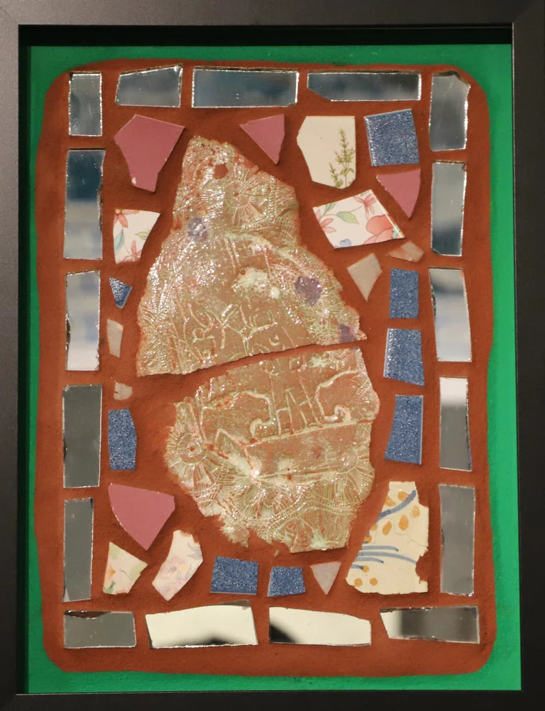 Framed mosaic with colorful tiles on orange grout with a green border.