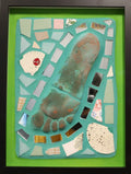 Framed mosaic featuring the mold of a foot with various colored tiles on blue grout with a green border.