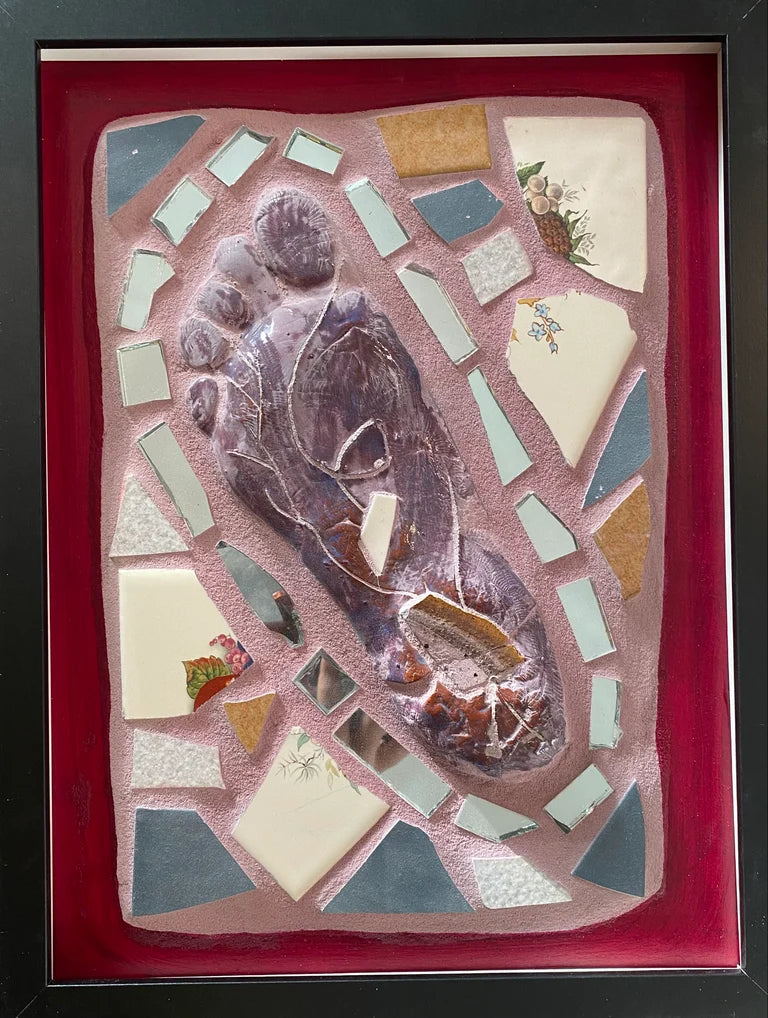 Framed mosaic featuring the mold of a foot against pink grout and a red border.