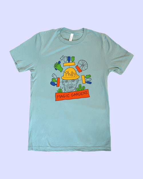 Dusty blue t-shirt with black, green, blue, yellow, and orange ink. Features an image of the head of PMG founder, Isaiah Zagar surrounded by bottles, bike wheels, a hand holding a trowel, and the words "Philly Magic Gardens."