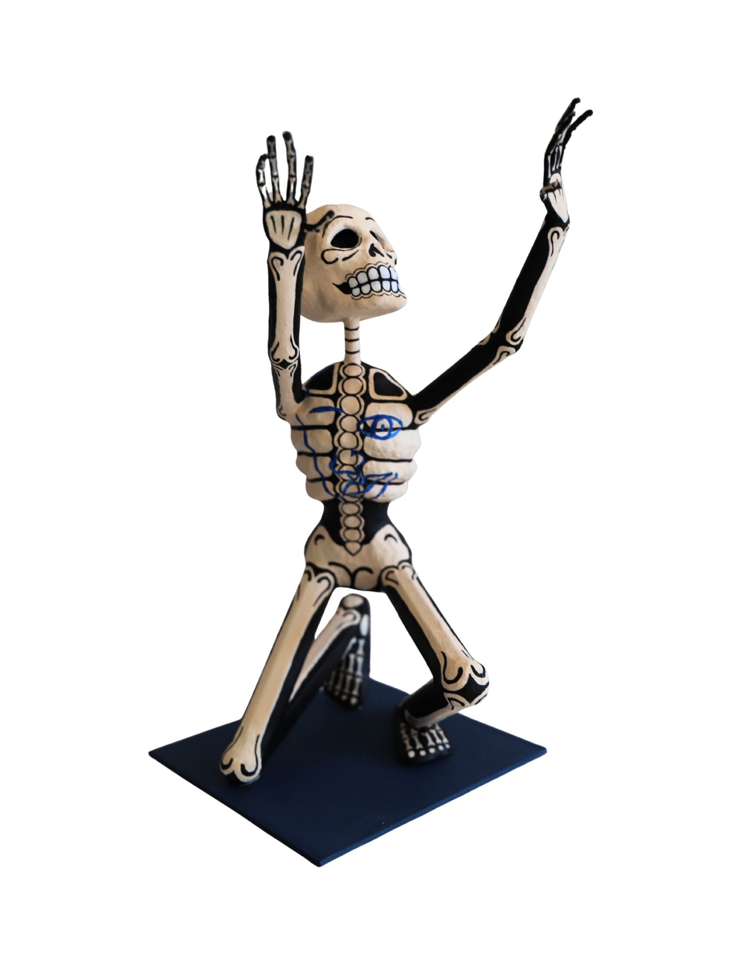A papier-mâché skeleton figurine posed kneeling with both arms raised.