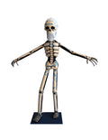 A papier-mâché skeleton figure with a white beard standing with outstretched arms.