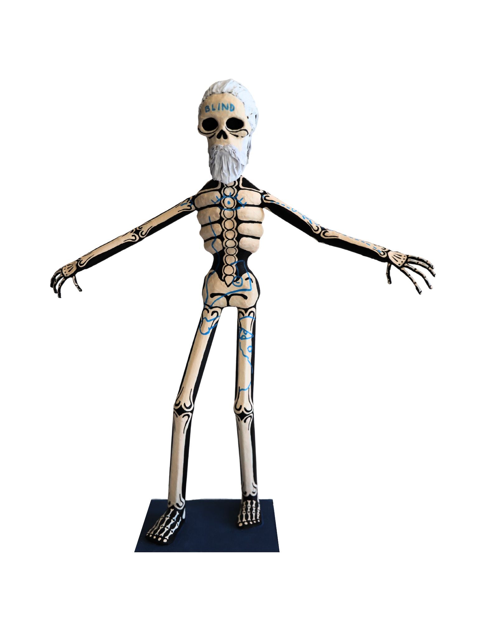 A papier-mâché skeleton figure with a white beard standing with outstretched arms.